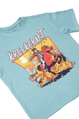 KreekCraft seafoam tee with KreekCraft riding a horse in a burning city artwork on the entire front, in close-up.
